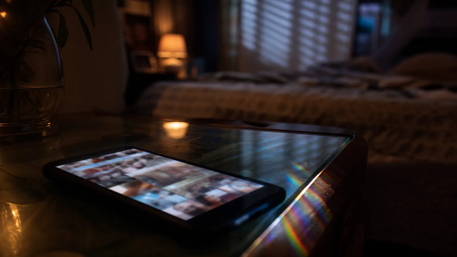 Soft phone screen glow with a blurred photo grid in a dim private room at night